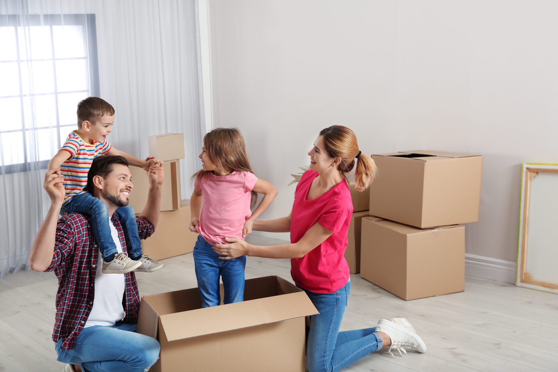 Happy family playing with cardboard box in their new house. Moving day Happy family playing with cardboard box in their new house. Moving day