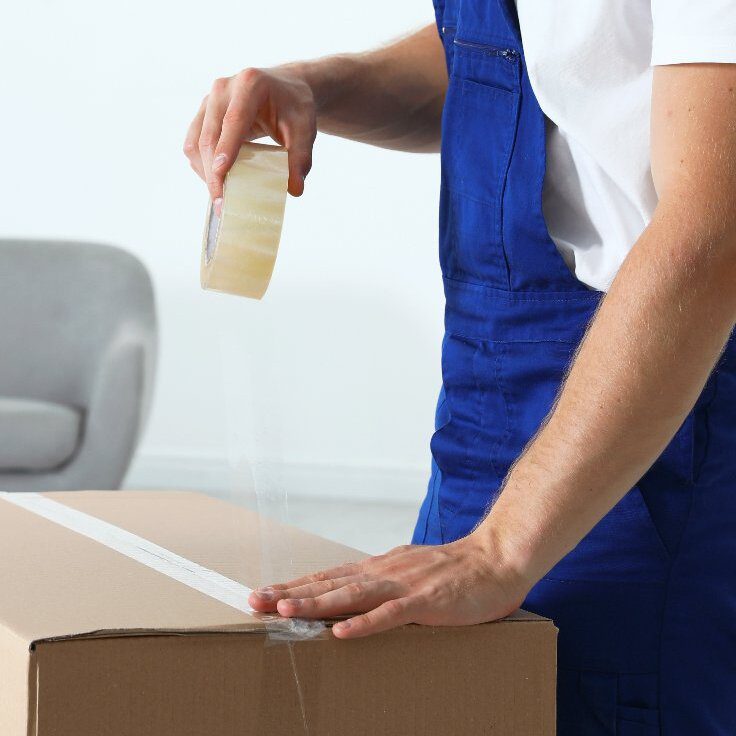 Moving service employee sealing cardboard box Moving service employee